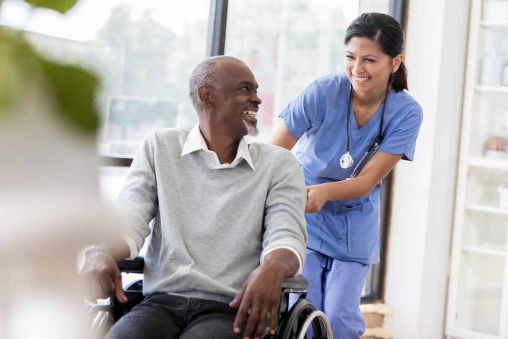 Young nurse and senior patient in a wheelchair smile at each other
